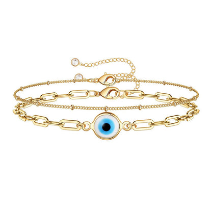 close up blue evil eye charm on gold paperclip chain bracelet